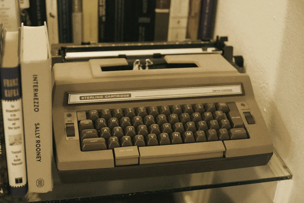 A typewriter beside a stack of books